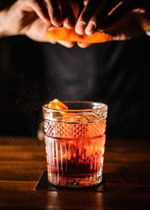 Bartender,With,Cocktail,And,Orange,Peel,Preparing,Cocktail,At,Bar.